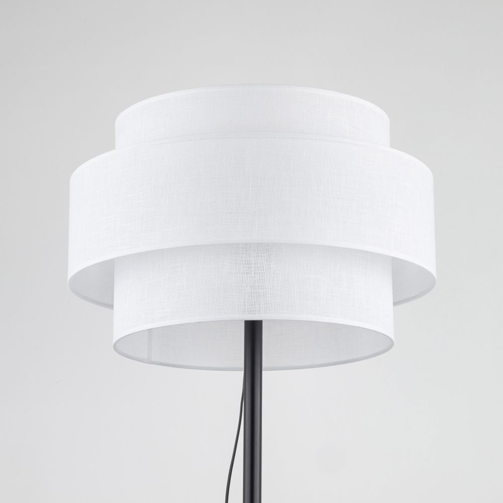 Lampa podłogowa z białym, dwuwarstwowym abażurem o nowoczesnym designie. Czarny stelaż z widocznym przewodem zasilającym.