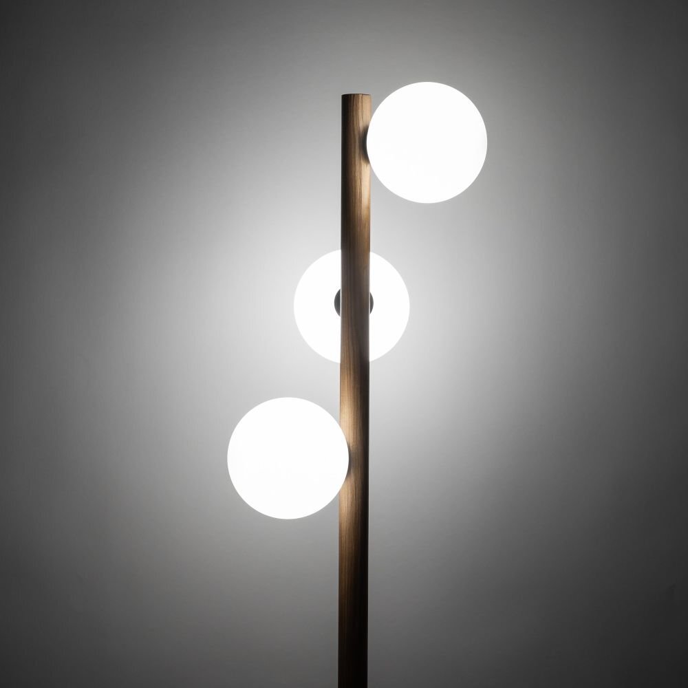 Lampa podłogowa z drewnianym trzonem i trzema białymi, kulistymi kloszami. Klosze są równomiernie rozmieszczone wzdłuż trzonu.
