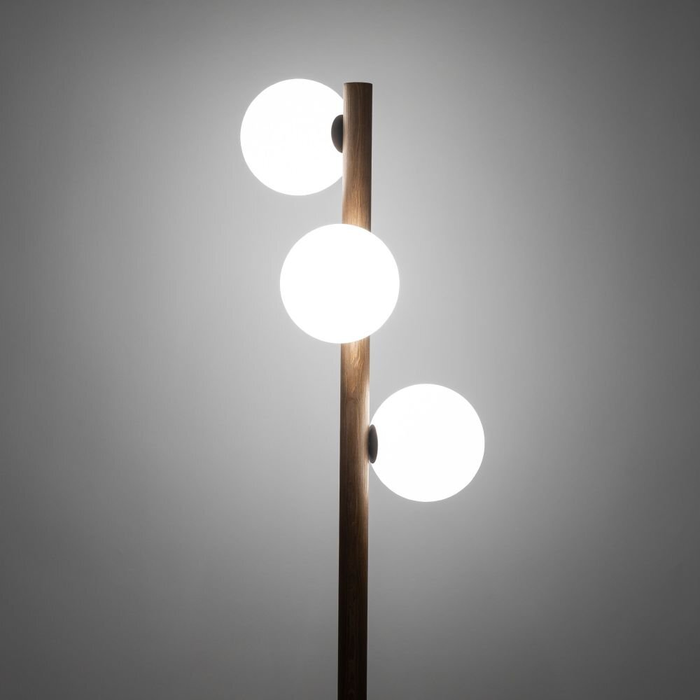 Lampa podłogowa z drewnianym trzonem i trzema białymi, kulistymi kloszami. Klosze są równomiernie rozmieszczone wzdłuż trzonu.