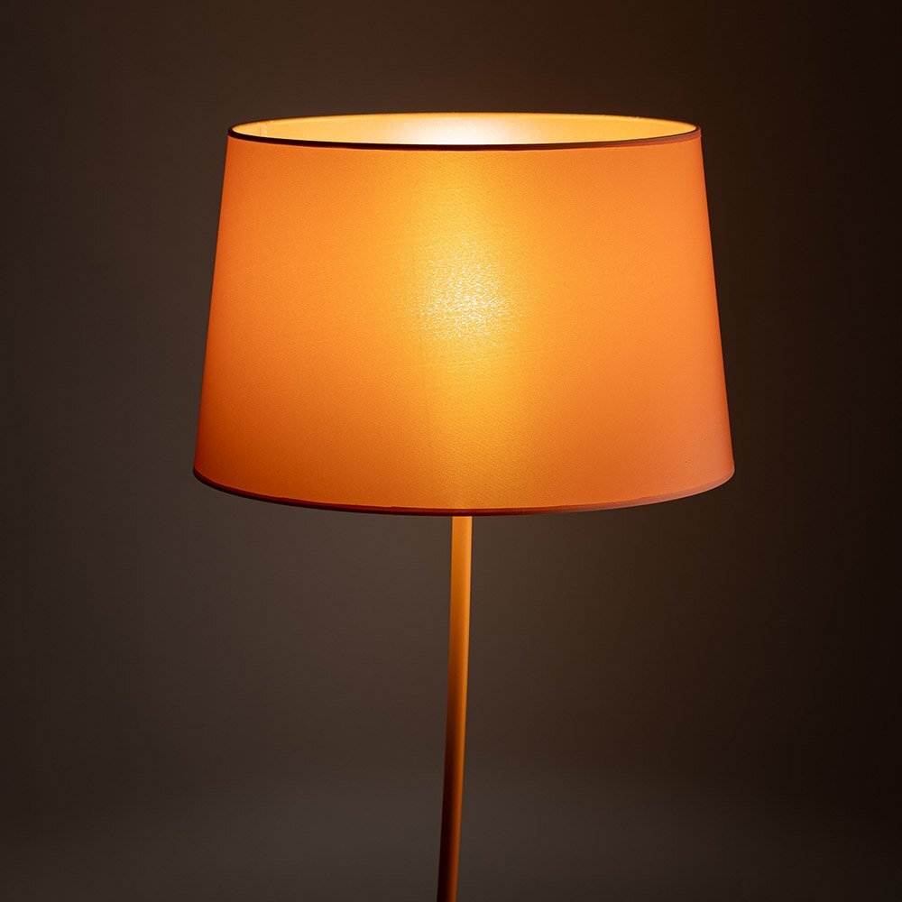 Lampa podłogowa z pomarańczowym abażurem, emitująca ciepłe światło. Abażur ma gładką powierzchnię i jest zamontowany na prostym metalowym stelażu.