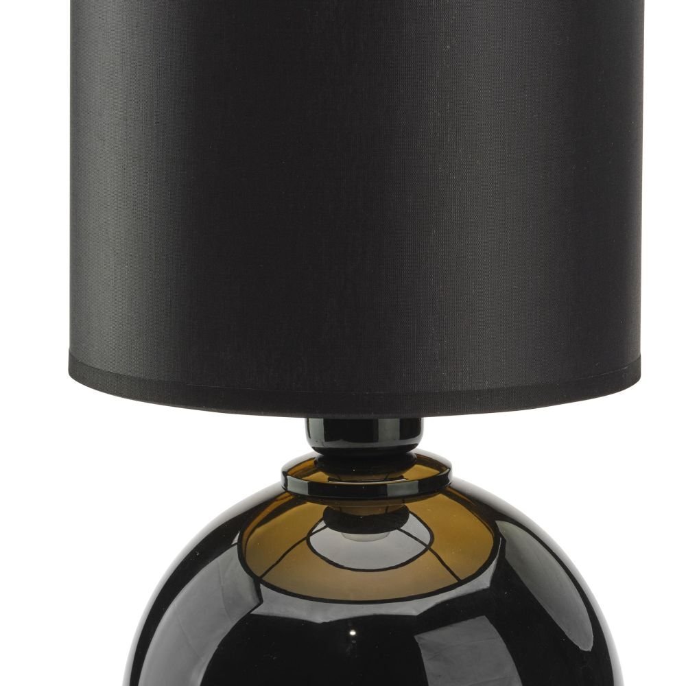 Czarna lampa stołowa z cylindrycznym abażurem i kulistą podstawą w kolorze czarnym ze złotymi akcentami. Powierzchnia jest błyszcząca, a materiał abażuru wydaje się być tekstylny.