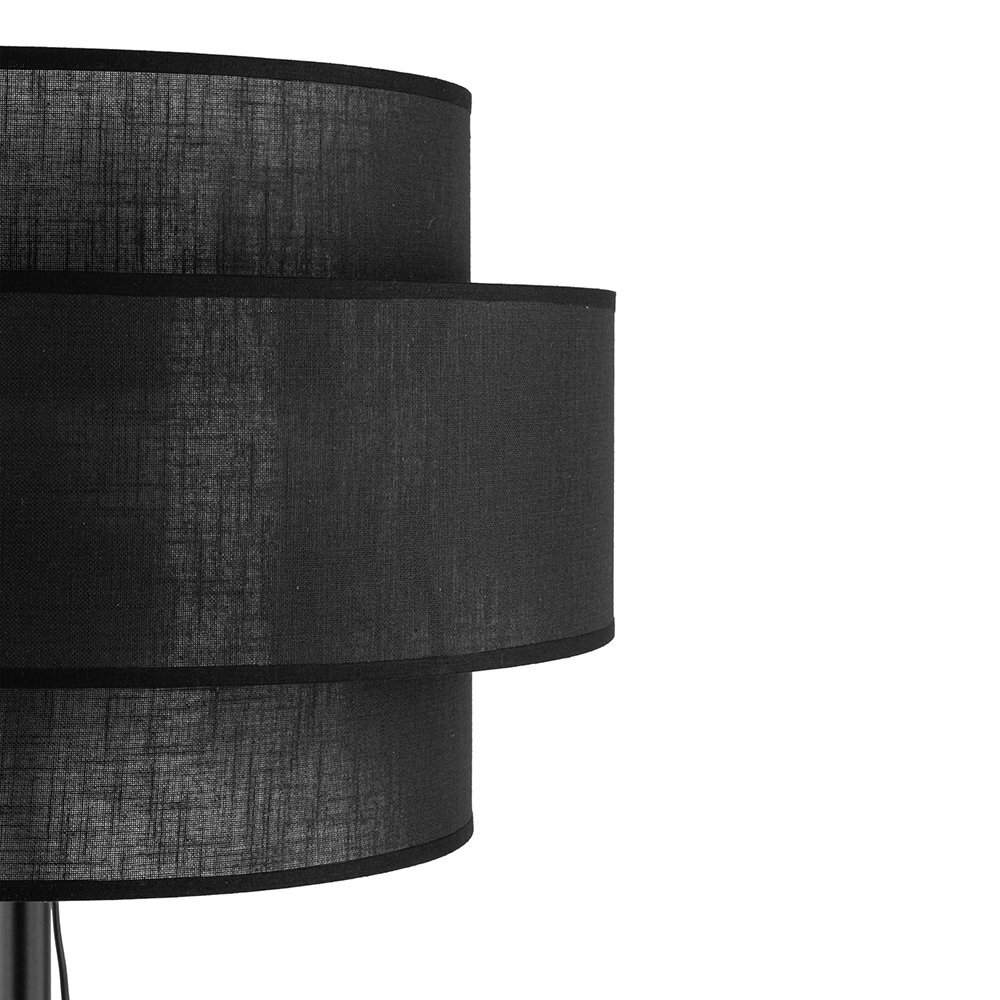 Czarna lampa podłogowa z metalowym stelażem i dwoma cylindrycznymi abażurami. Abażury mają teksturę przypominającą tkaninę.