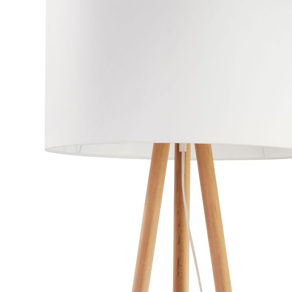 Lampa podłogowa z białym, tkaninowym abażurem i drewnianymi nogami. Przewód z włącznikiem widoczny jest pomiędzy nogami lampy.