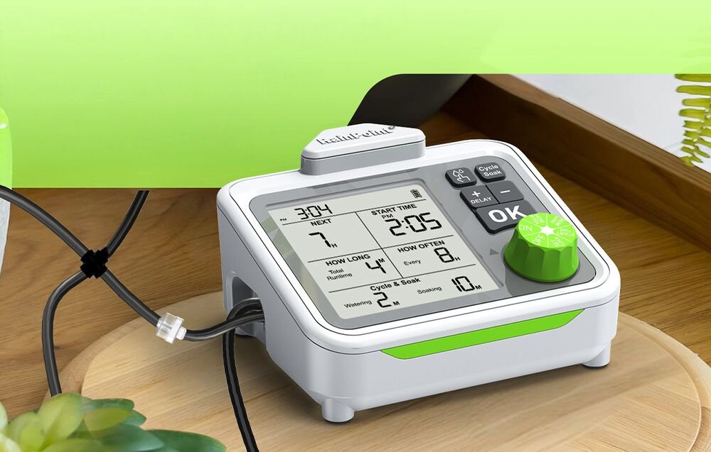 Wewnętrzny zestaw pompy do podlewania RAINPOINT IK153, tryb ręczny, opóźnienie, bateria, działanie, Urządzenie do automatycznego nawadniania stojące na drewnianej podstawce przy zielonej ścianie.