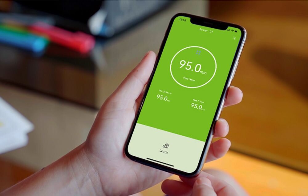 Czujnik deszczu RAINPOINT HCS012ARF, RainPoint, aplikacja, historia, wykresy, Dłoń trzymająca smartfon z uruchomioną aplikacją pokazującą odczyt opadów wynoszący 95 mm.