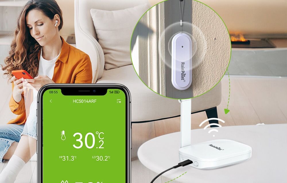 Inteligentny Termohigrometr RAINPOINT Smart+, RainPoint, wykresy, historia, analiza, Kobieta sprawdza w telefonie dane z czujnika RainPoint, który przesyła sygnał do stacji bazowej na stole.