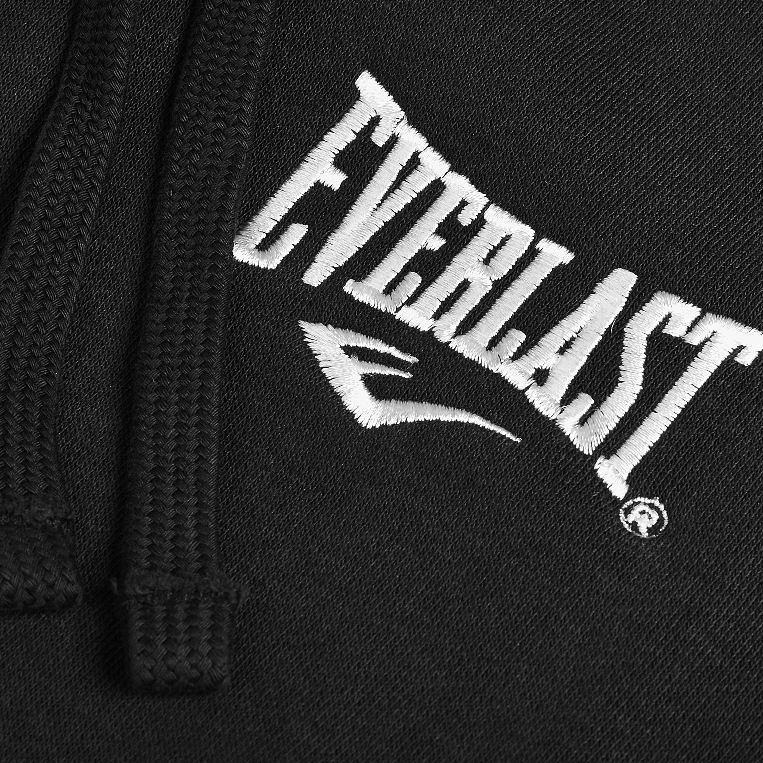 Czarna tkanina z białym haftem przedstawiającym napis \'EVERLAST\' oraz stylizowaną literę \'E\'. Obok widoczny jest sznurek, prawdopodobnie od bluzy.