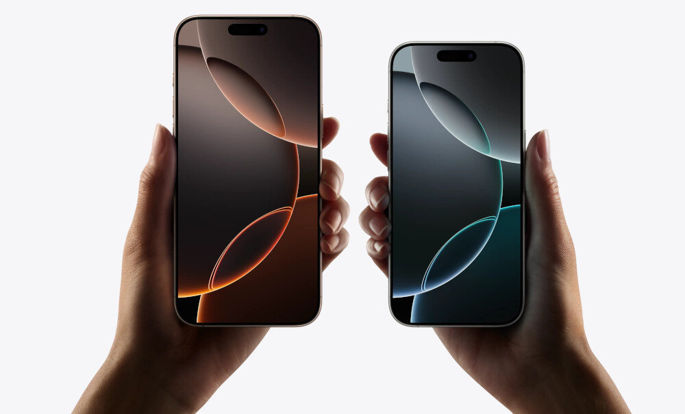 Dwa smartfony trzymane w dłoniach, każdy z wyświetlaczem pokazującym abstrakcyjny wzór w odcieniach brązu i zieleni. Obudowy urządzeń są w kolorze metalicznym.