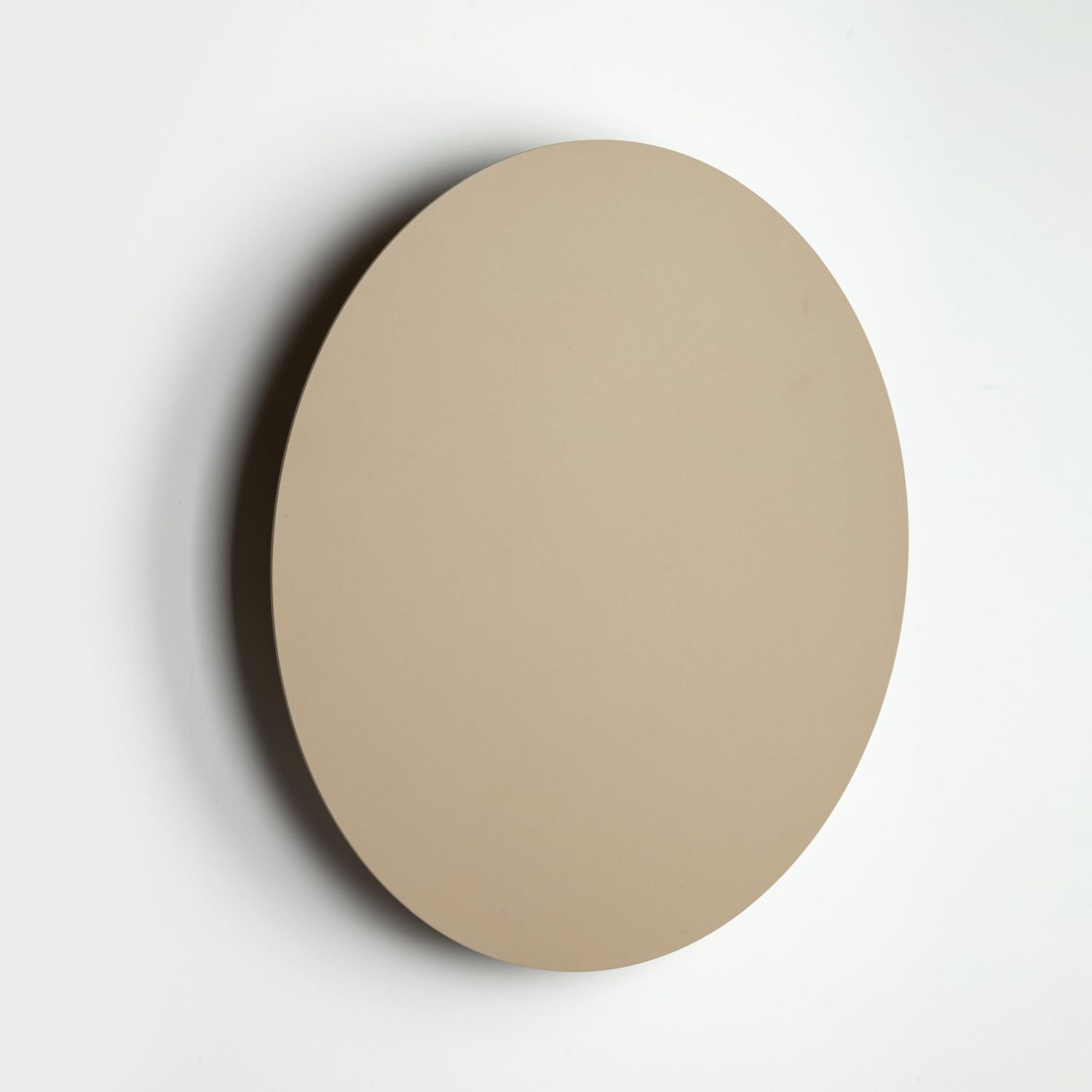 Beżowy, okrągły kinkiet o gładkiej powierzchni zamontowany na ścianie. Lampa ma minimalistyczny design.