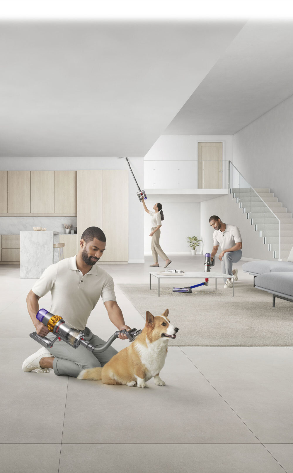 Trzy osoby używają odkurzacza bezprzewodowego w nowoczesnym salonie z kuchnią. Na podłodze siedzi pies, a w tle widać schody i meble.