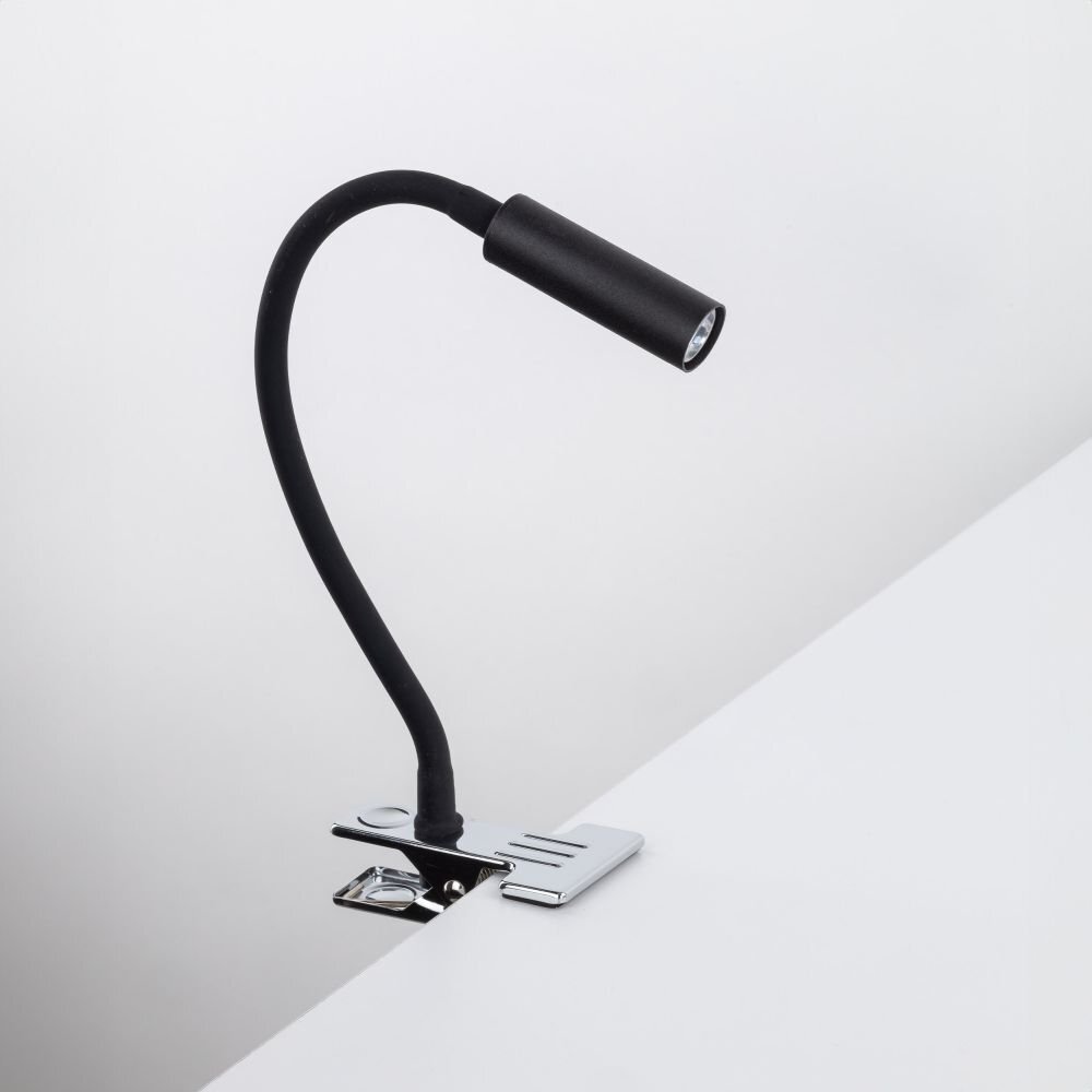 Czarna lampa biurkowa z klipsem przymocowana do białej powierzchni. Lampa ma elastyczne ramię i metalowy klips w kolorze srebrnym.