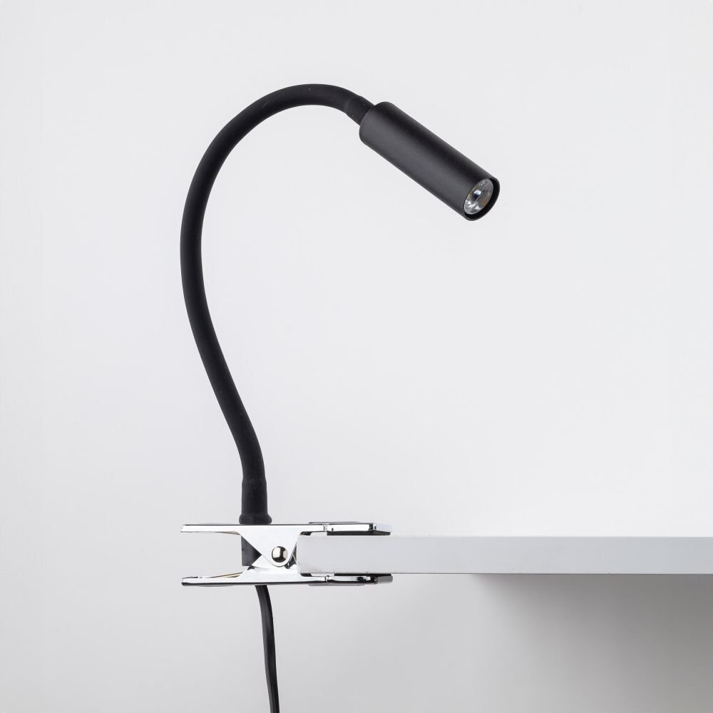 Czarna lampa biurkowa z klipsem przymocowana do krawędzi blatu. Posiada elastyczne ramię i metalowy klosz.