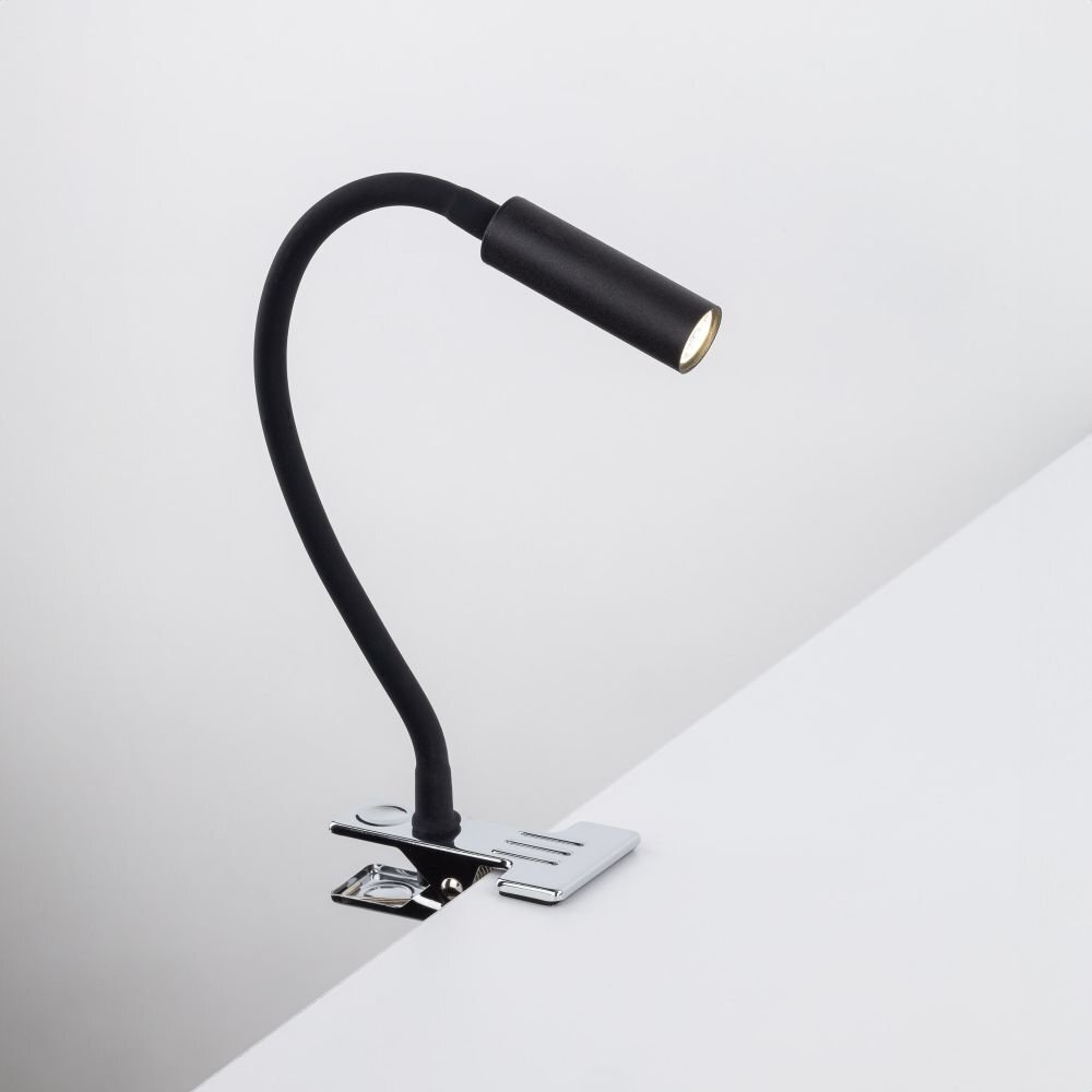 Czarna lampa biurkowa z klipsem przymocowana do białej powierzchni. Lampa ma elastyczne ramię i cylindryczny klosz.