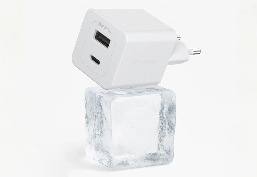 Biała ładowarka sieciowa z dwoma portami USB, oznaczona napisem \'35W TOTAL\' i \'empower\', stoi na przezroczystej kostce lodu.