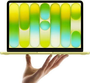 Laptop z kolorowym, abstrakcyjnym wzorem na ekranie jest trzymany w powietrzu przez dłoń. Obudowa laptopa ma jasny kolor.