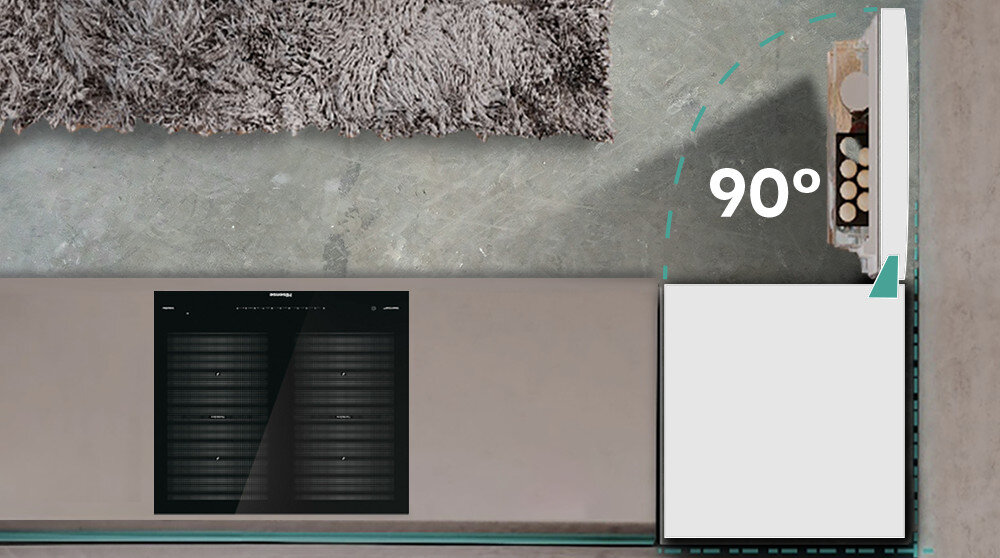 Widok z góry na otwartą lodówkę ustawioną pod kątem 90 stopni, obok której znajduje się szara powierzchnia i dywan. Na lodówce widoczny jest napis \'90°\'.