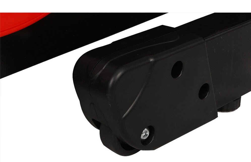 Czarny element konstrukcyjny z dwoma otworami i widocznym kółkiem. W tle fragment czerwonego elementu.