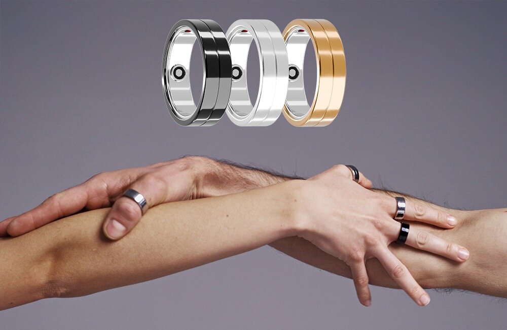 Na obrazie widoczne są trzy pierścienie w kolorach czarnym, srebrnym i złotym, unoszące się nad splecionymi rękami osób noszących podobne pierścienie. Tło jest jednolite, szare.