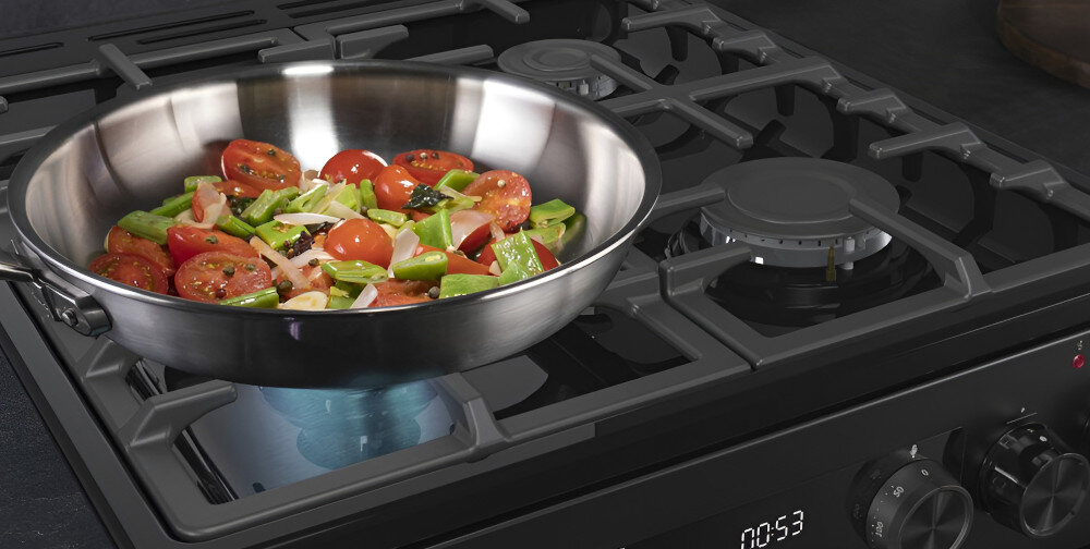 Na kuchence gazowej znajduje się patelnia z pokrojonymi pomidorami, papryką i innymi warzywami. Panel sterowania pokazuje czas 00:53.