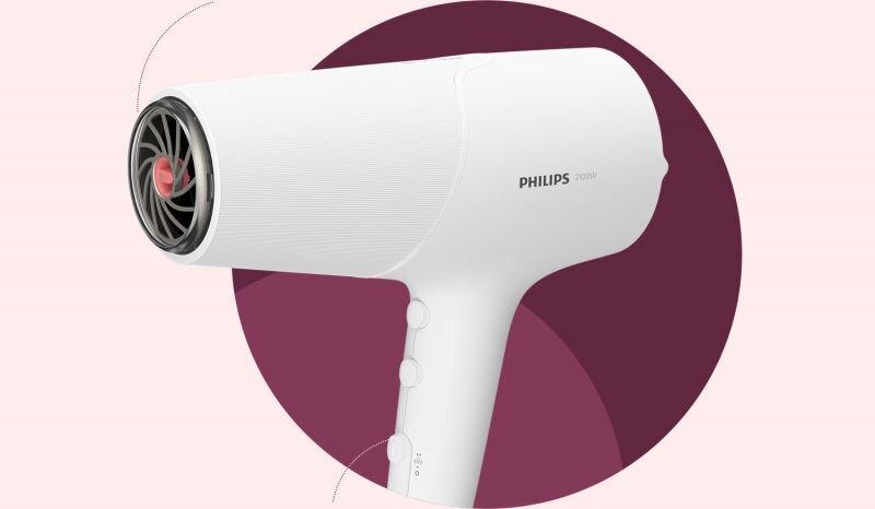 Biała suszarka do włosów z widocznym logo PHILIPS 2100W, umieszczona na tle w kształcie koła w kolorze bordowym. Suszarka ma trzy przyciski na uchwycie i widoczny wentylator z przodu.