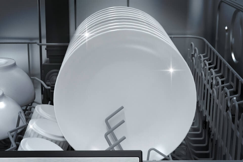 Wnętrze zmywarki z widocznymi białymi talerzami ustawionymi w stojaku. Talerze są czyste i błyszczące.