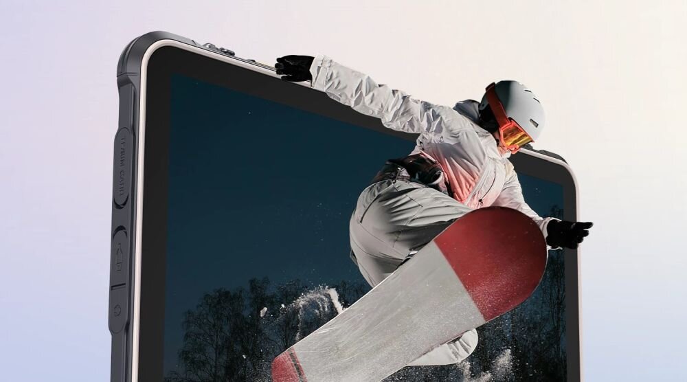 Osoba na snowboardzie wydaje się wychodzić z ekranu tabletu, który ma szary obramowanie i widoczne przyciski boczne. Tło jest jasne, a na ekranie widać zimowy krajobraz.