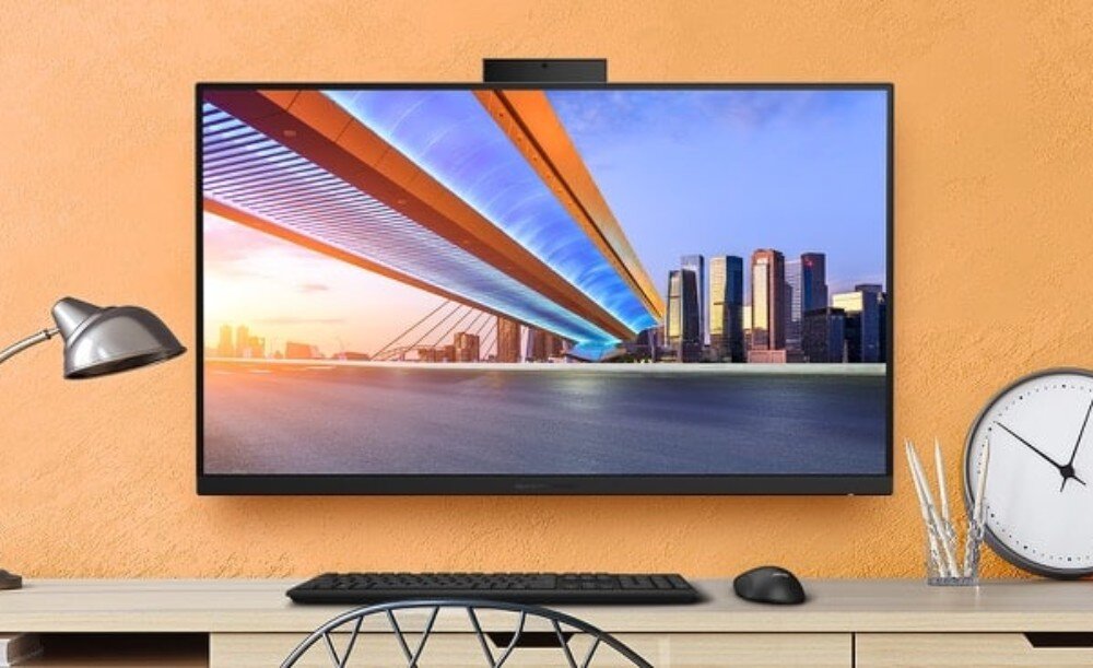 Komputer All in One ASUS ExpertCenter PM670KA-BPE046X Komputer zamontowany na pomarańczowej ścianie nad biurkiem obok lampki i zegara wyświetlający zdjęcie nowoczesnego mostu oraz wieżowców, podstawka, regulacja, mocowanie VESA