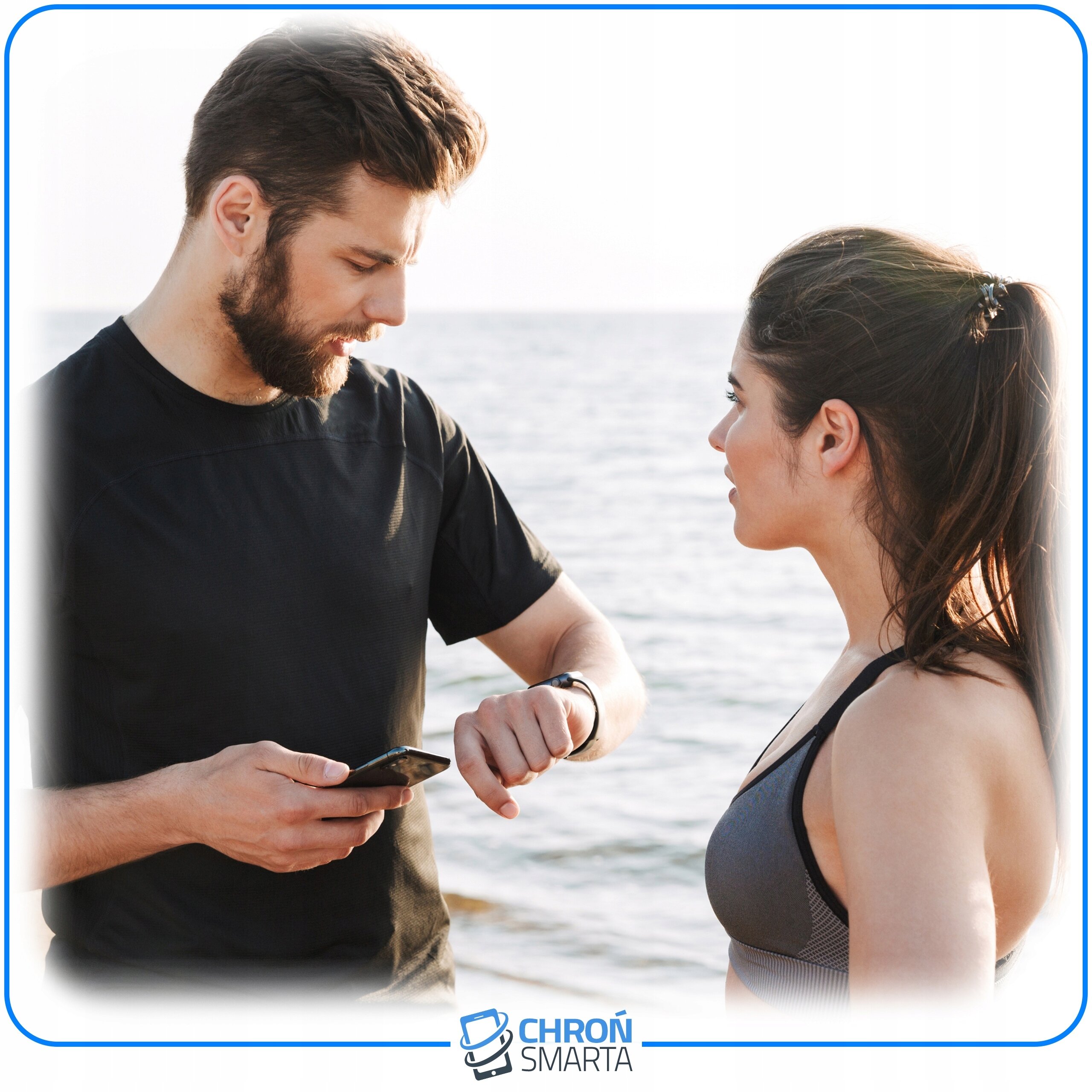 Na zdjęciu widać dwie osoby stojące na plaży, jedna z nich trzyma telefon, a druga patrzy na smartwatch. Na dole zdjęcia znajduje się logo z napisem \'CHROŃ SMARTA\'.