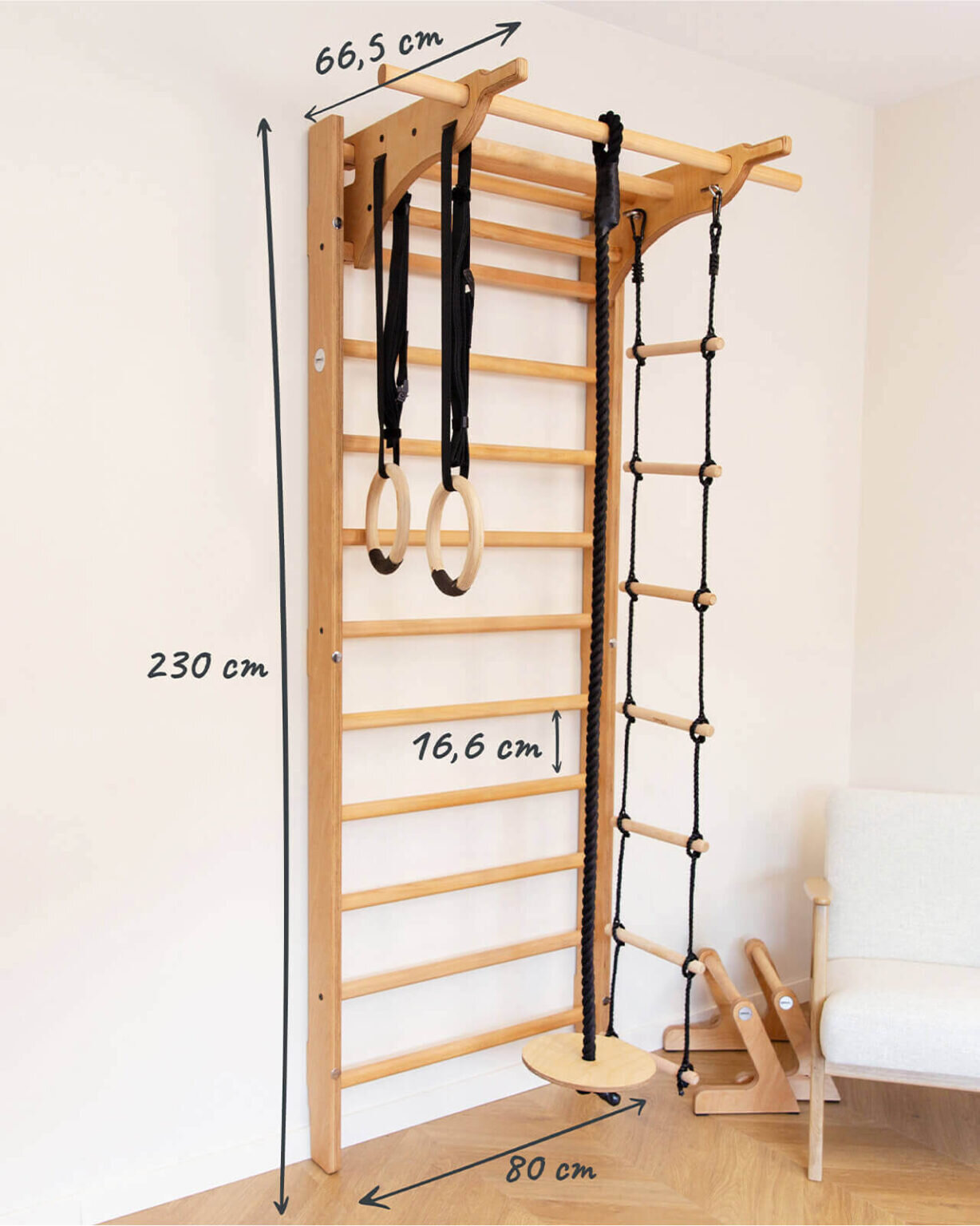 Drabinka gimnastyczna z drewna z zamontowanymi kółkami gimnastycznymi i liną z drabinką. Wymiary: 230 cm wysokości, 66,5 cm szerokości, 16,6 cm odstępu między szczeblami, 80 cm głębokości.