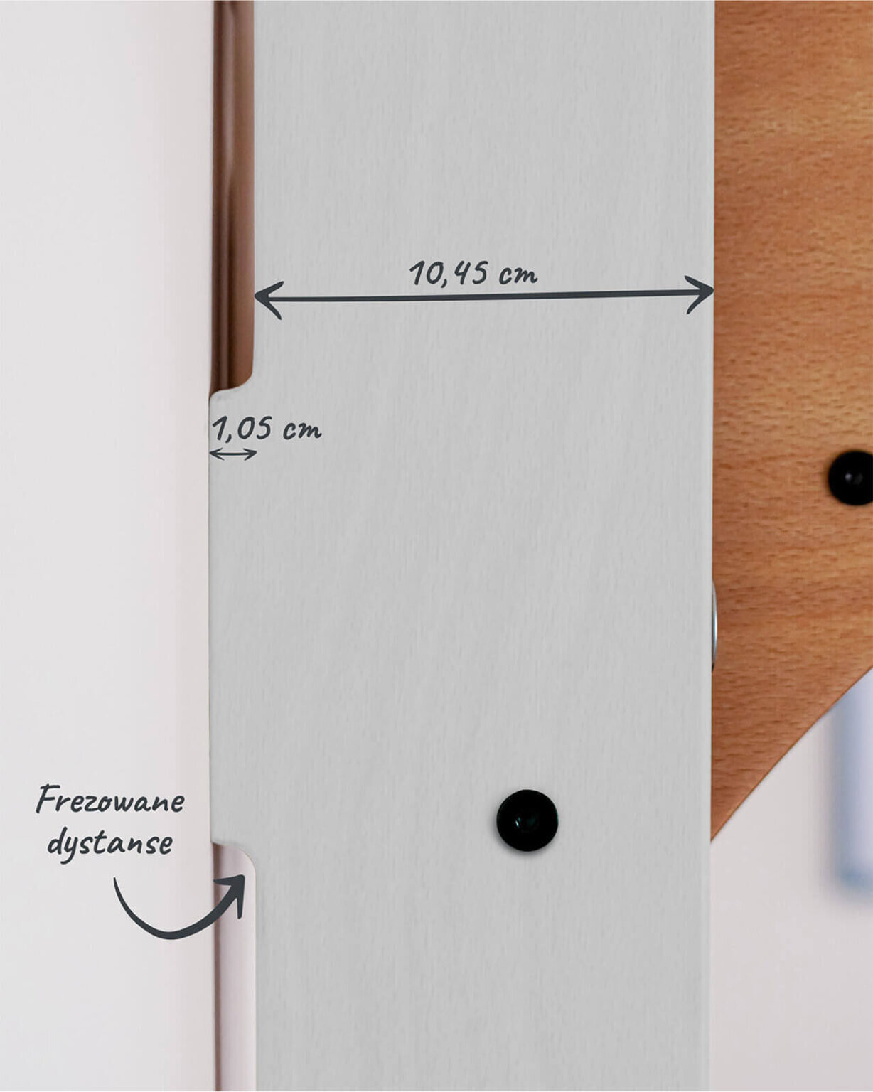 Zbliżenie na białą powierzchnię z oznaczeniami wymiarów: 10,45 cm i 1,05 cm oraz tekstem \'Frezowane dystanse\'.