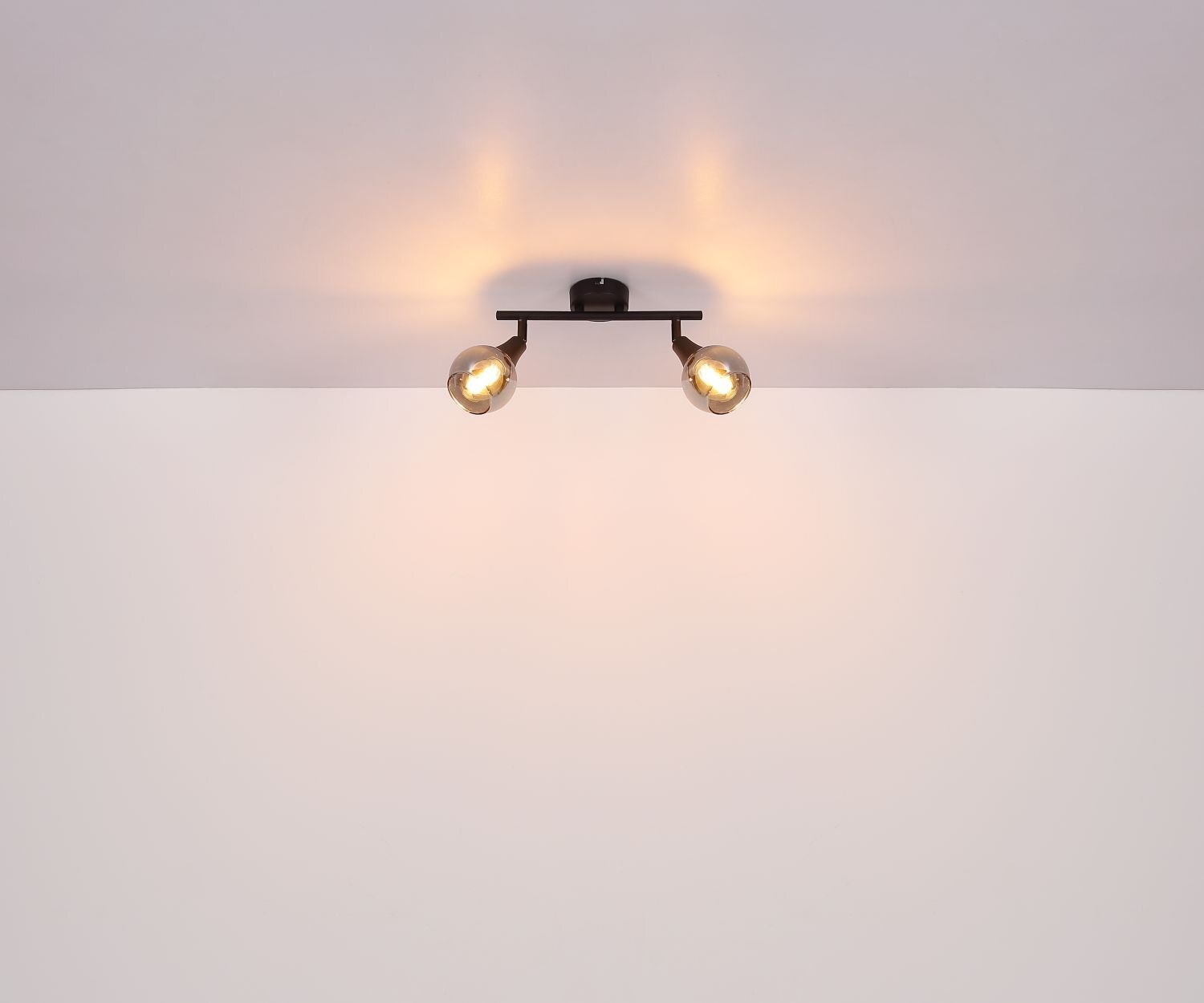 Na suficie zamontowana jest lampa sufitowa z dwoma reflektorami, emitująca ciepłe światło. Lampa ma nowoczesny design i jest w kolorze czarnym.