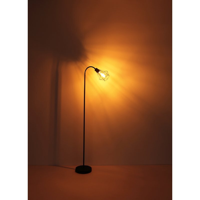 Czarna matowa lampa podłogowa z metalową siatką, emitująca ciepłe, żółte światło na ścianę. Lampa posiada smukły, zakrzywiony trzon i okrągłą podstawę.