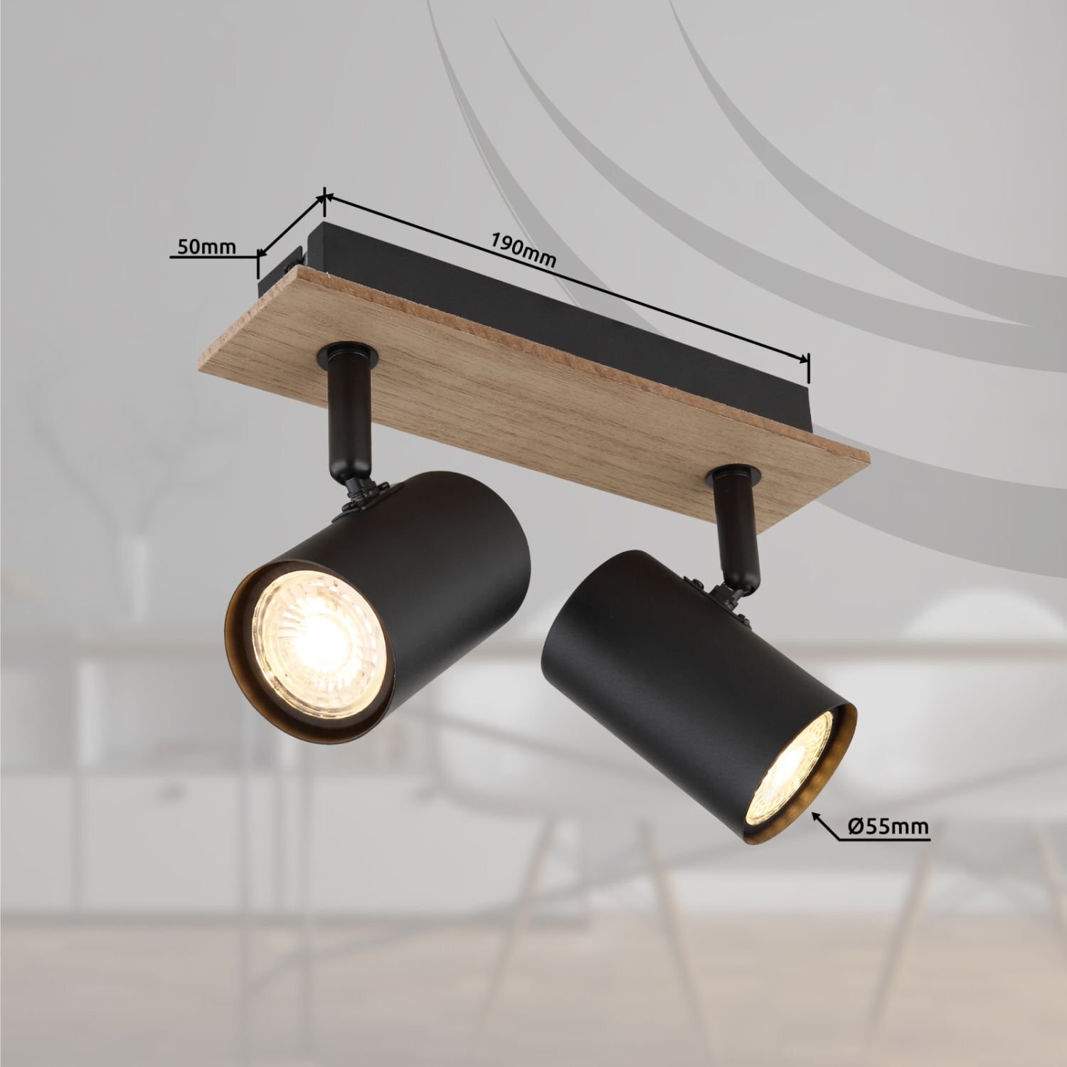 Na obrazie widoczna jest lampa reflektorowa z dwoma czarnymi punktami świetlnymi zamontowanymi na drewnianej podstawie. Wymiary to 190 mm długości, 50 mm szerokości i 55 mm średnicy reflektorów.