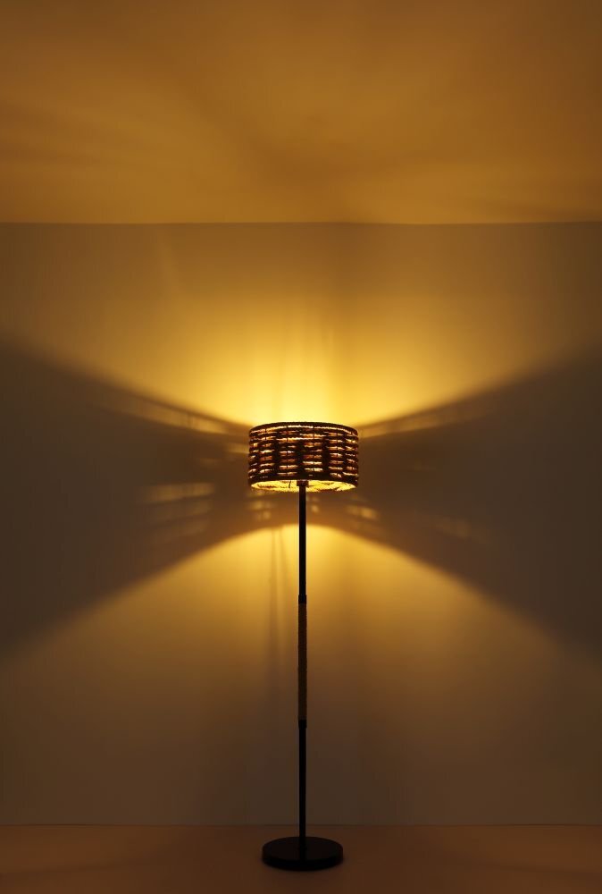 Lampa stołowa z czarnym matowym wykończeniem i abażurem z liny konopnej, emitująca ciepłe, rozproszone światło na ścianę.