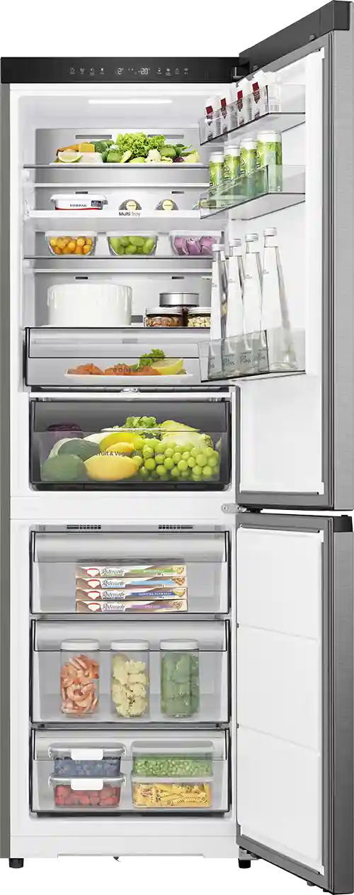 Otwarta lodówka z widocznymi półkami wypełnionymi różnorodnymi produktami spożywczymi, takimi jak warzywa, owoce, napoje i pojemniki z jedzeniem. Na drzwiach znajdują się butelki i kartony, a na panelu sterowania widoczne są przyciski i wyświetlacz cyfrowy.