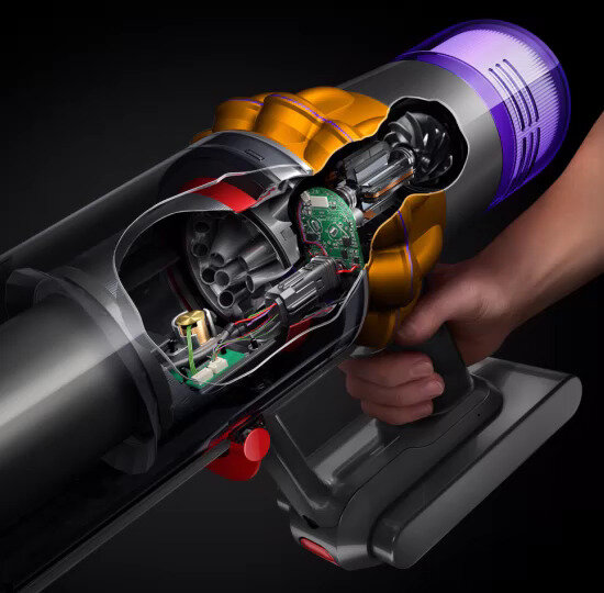 Obraz przedstawia wnętrze odkurzacza z widocznymi elementami elektronicznymi i mechanicznymi. Urządzenie trzymane jest w dłoni, a jego obudowa jest częściowo przezroczysta, ukazując wewnętrzne komponenty.