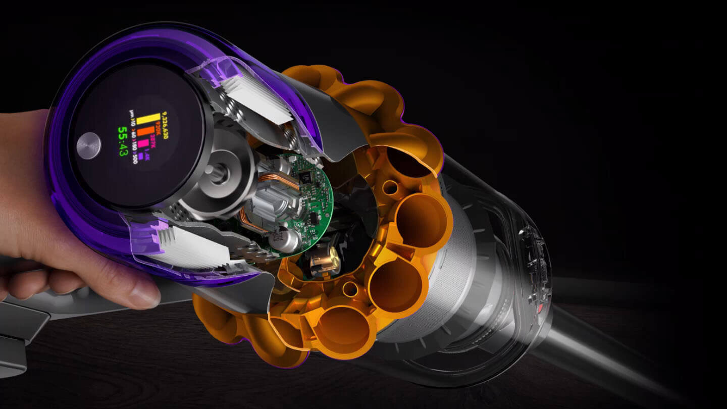 Obraz przedstawia wnętrze odkurzacza z widocznymi elementami technologicznymi i kolorowym wyświetlaczem. Na wyświetlaczu widoczny jest tekst: \'55:43\'.