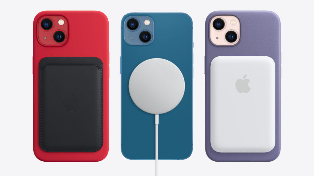 Trzy smartfony z widocznymi akcesoriami: czerwony z czarnym etui, niebieski z białą ładowarką magnetyczną oraz fioletowy z białym powerbankiem. Na każdym z urządzeń widoczne jest logo w kształcie nadgryzionego jabłka.