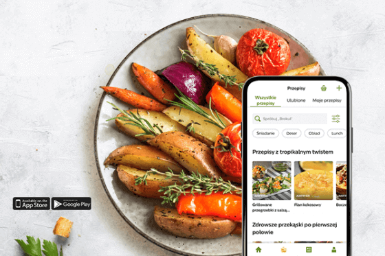 Na talerzu znajdują się pieczone warzywa, a obok widoczny jest smartfon z aplikacją kulinarną. Na ekranie telefonu widać przepisy oraz kategorie takie jak \'Śniadanie\', \'Deser\', \'Obiad\', \'Lunch\'.