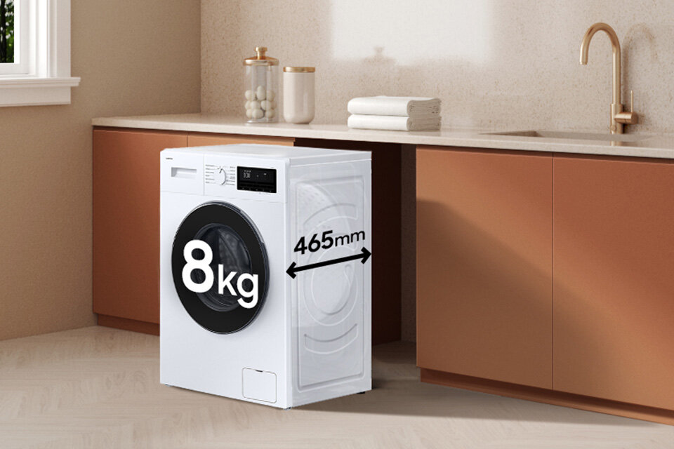 Pralka o białej obudowie stoi w kuchni z brązowymi szafkami. Na drzwiach pralki widoczny jest napis \'8kg\', a obok \'465mm\'.