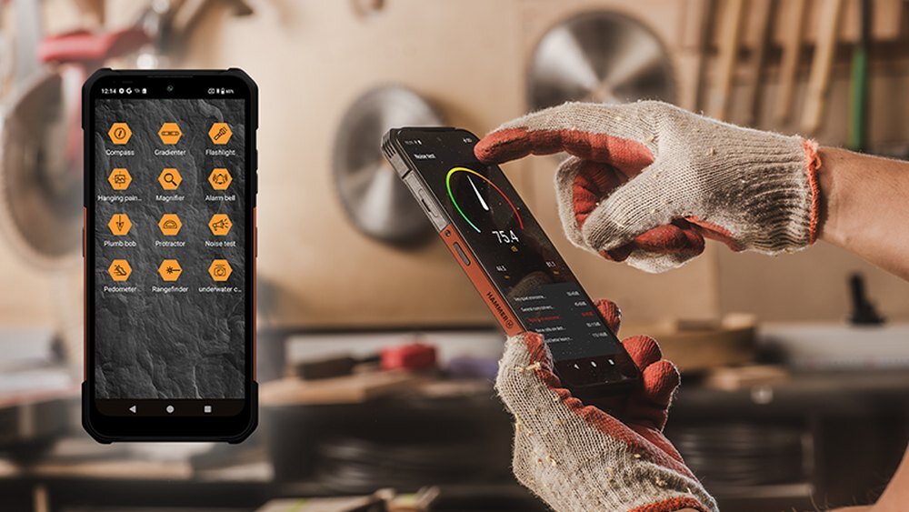 Na zdjęciu widać dwa smartfony w warsztacie, jeden z wyświetlonymi ikonami aplikacji, a drugi z aplikacją pokazującą wykres i liczbę 75.4. Osoba w rękawicach dotyka ekranu jednego z telefonów.