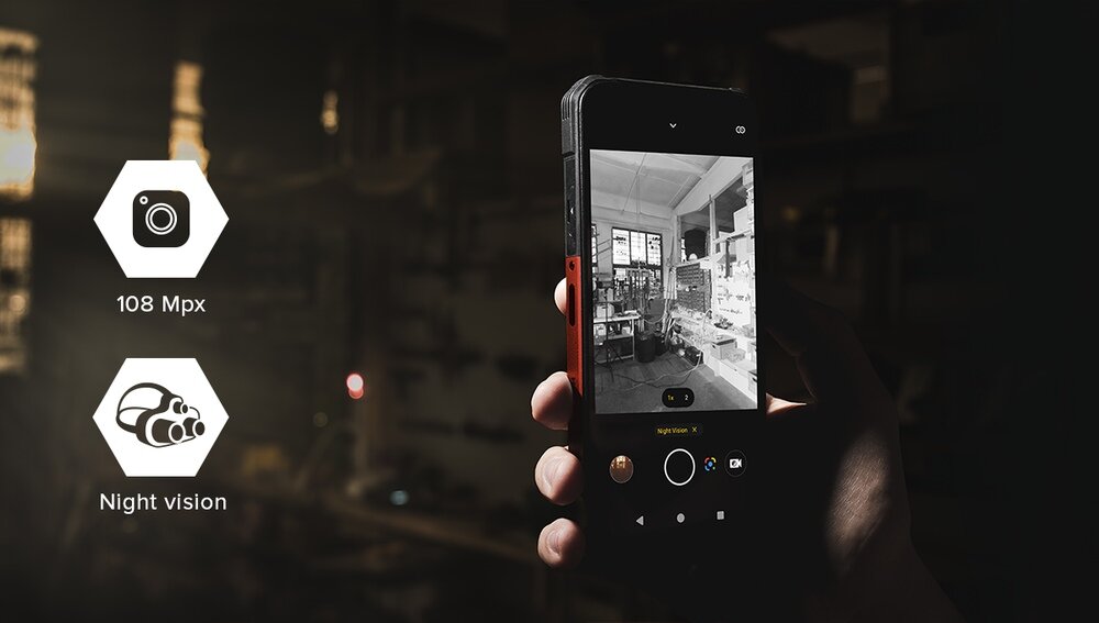 Osoba trzyma smartfon, na ekranie którego widać obraz w trybie nocnym przedstawiający wnętrze pomieszczenia. Obok telefonu znajdują się ikony z napisami \'108 Mpx\' i \'Night vision\'.