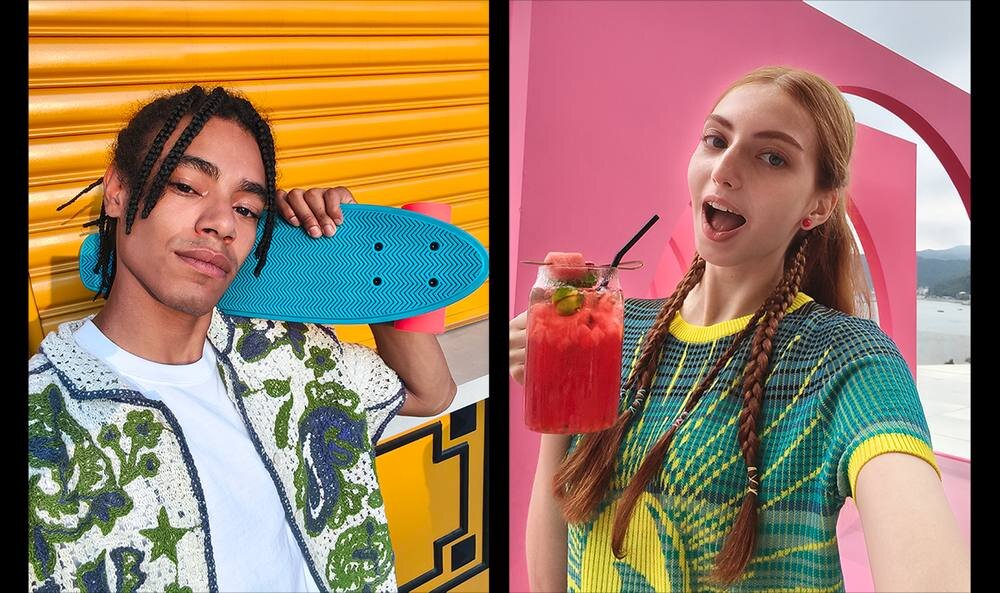 Dwie osoby pozują do zdjęć; jedna trzyma niebieską deskorolkę, a druga trzyma szklankę z czerwonym napojem i słomką. Tło jest kolorowe, z żółtymi i różowymi elementami.