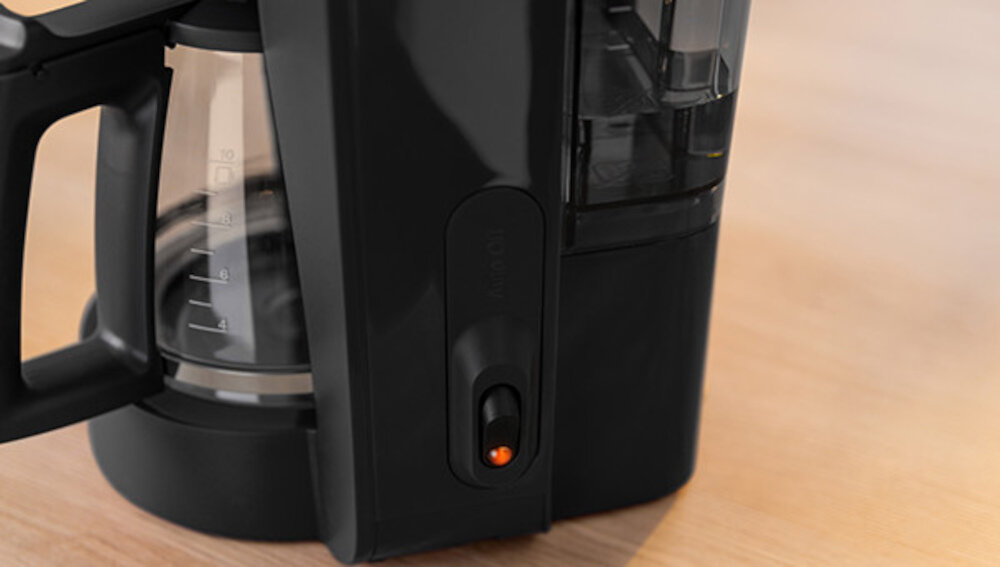 Czarny ekspres do kawy z widocznym szklanym dzbankiem z miarką oraz włącznikiem z pomarańczowym wskaźnikiem. Na obudowie znajduje się napis \'BOSCH\'.