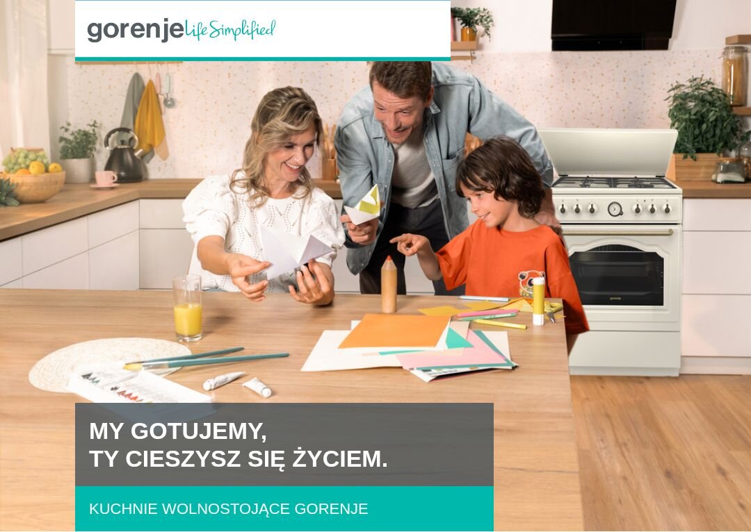 Na obrazie widać kuchnię z białą kuchenką i rodziną przy stole, zajmującą się pracami plastycznymi. Widoczny tekst: \'MY GOTUJEMY, TY CIESZYSZ SIĘ ŻYCIEM. KUCHNIE WOLNOSTOJĄCE GORENJE\'.