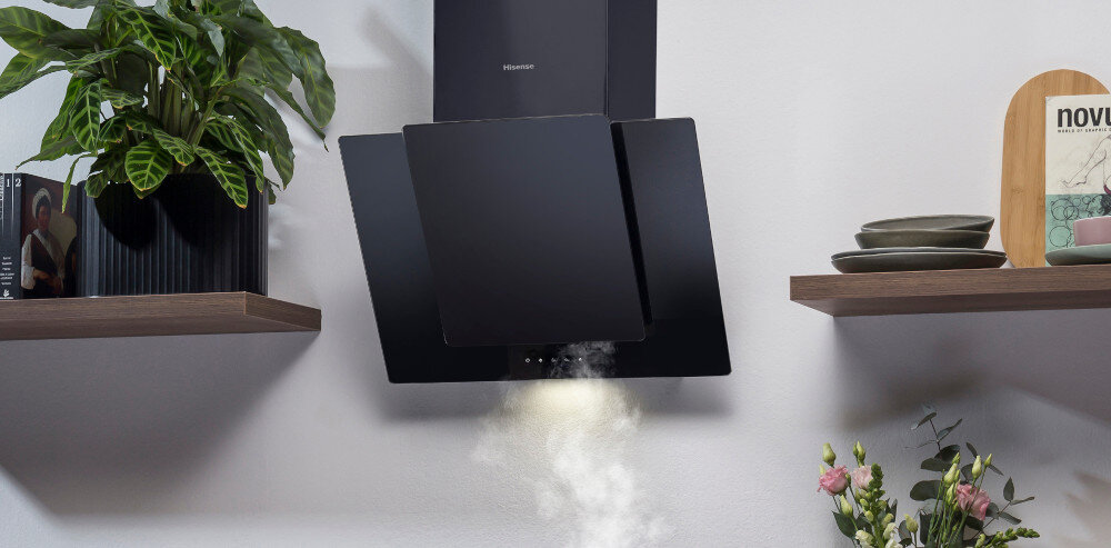 Czarny okap kuchenny zamontowany na ścianie, z którego wydobywa się para. Po bokach znajdują się półki z roślinami i naczyniami.