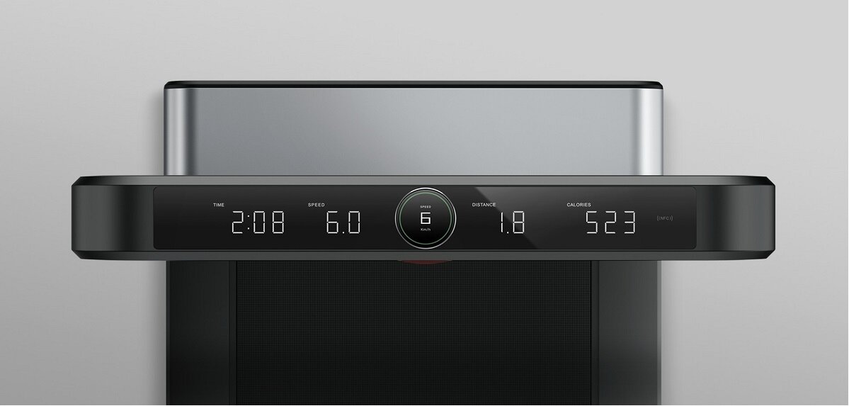Panel sterowania bieżni elektrycznej z wyświetlaczem pokazującym czas 2:08, prędkość 6.0, dystans 1.8 oraz spalone kalorie 523. Centralnie znajduje się okrągły przycisk z cyfrą 6.