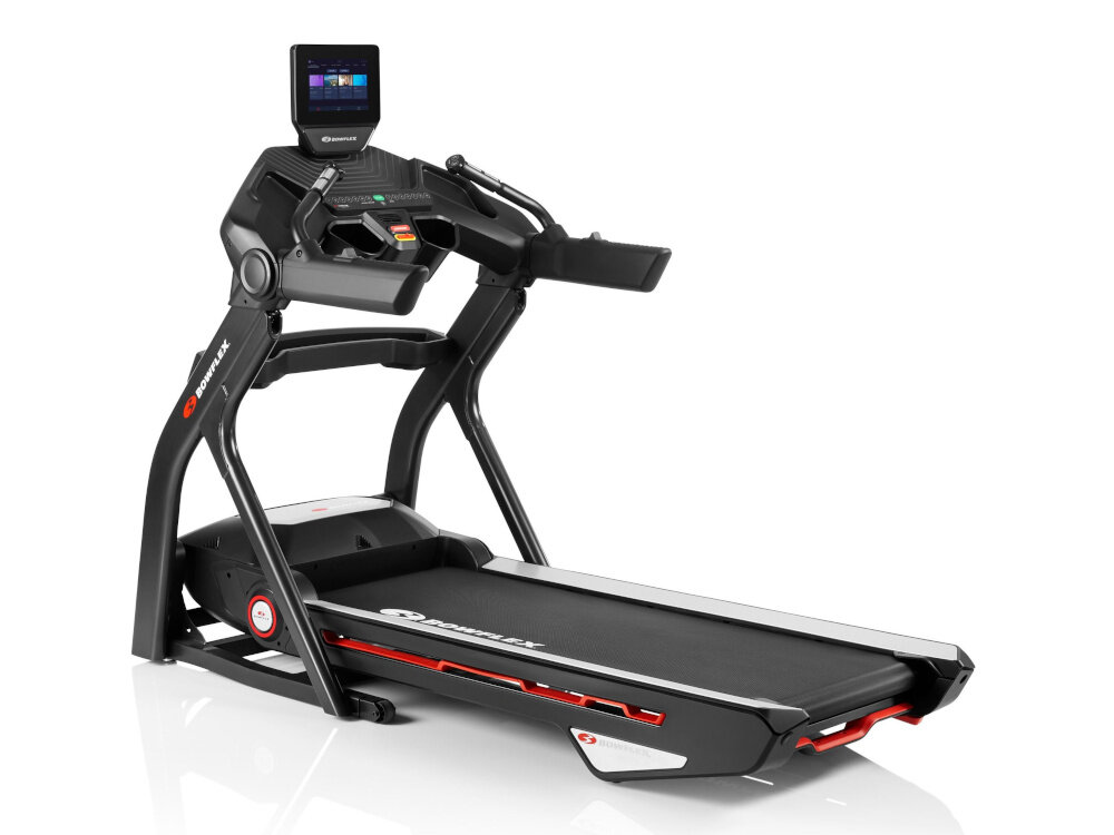 Na obrazie widoczna jest bieżnia elektryczna z czarną konstrukcją i wyświetlaczem na górze. Na bieżni znajduje się logo \'Bowflex\'.