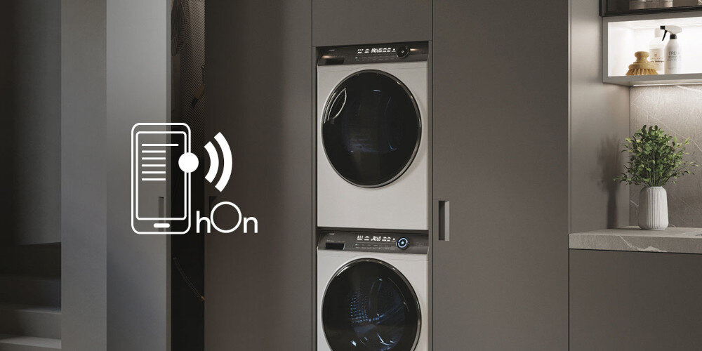Na obrazie widoczna jest suszarka w zabudowie z panelem sterowania, a obok niej znajduje się ikona smartfona z napisem \'hOn\'.