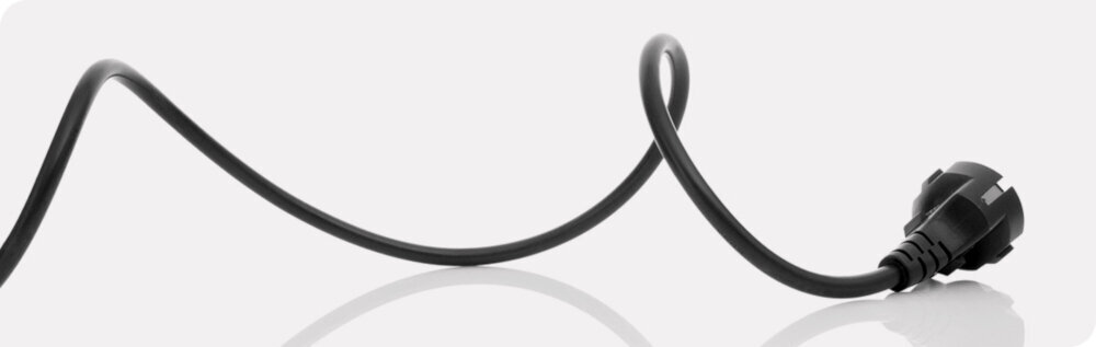 Czarny kabel z wtyczką na jasnym tle, ułożony w falisty kształt.
